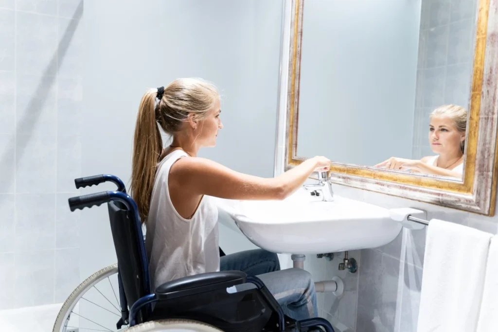 Disabled woman in wheelchair in bathroom looking in mirror