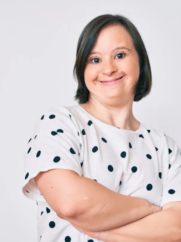 Girl with down syndrome smiling at camera with arms crossed